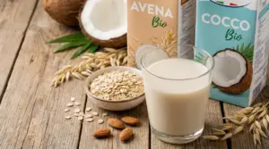 Bicchiere di bevanda vegetale con fiocchi d’avena, mandorle e cocco su tavolo rustico