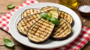 Fette di melanzane grigliate servite su un piatto con guarnizione di basilico